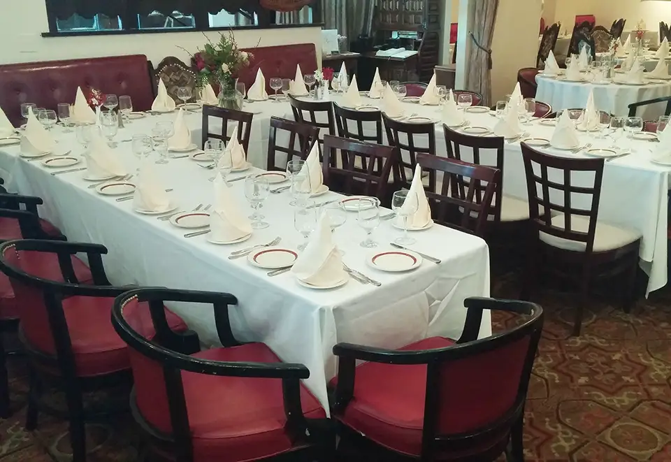 Banquet tables set for dining with white tablecloths and red/black chairs